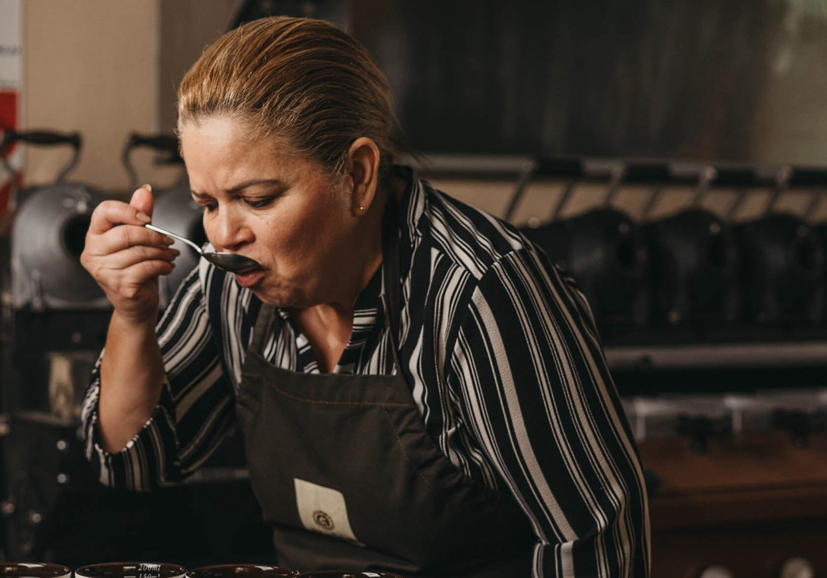 Maestra catadora degustando una taza de café durante una sesión de cata.