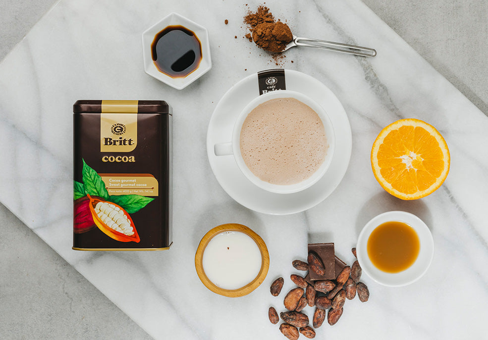 Ingredientes para preparar chocolate caliente con café, especias y rodajas de naranja.