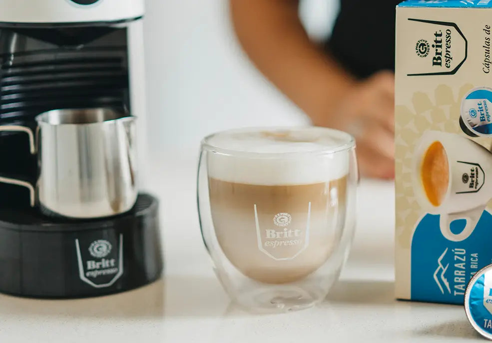 Cappuccino con crema irlandesa servido junto a máquina y cápsulas Café Britt.