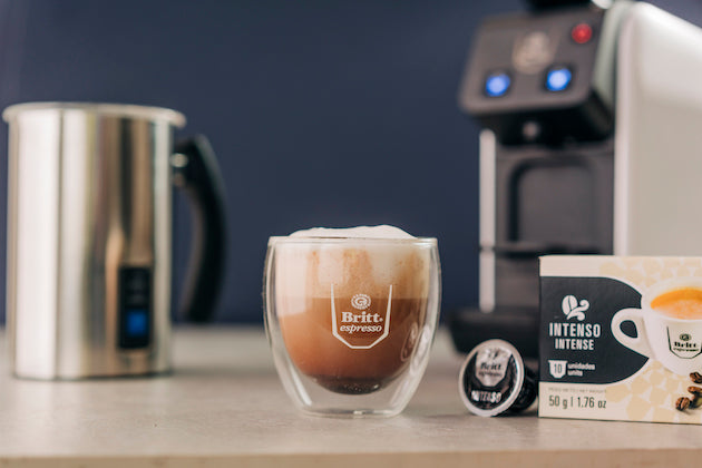 Café mocha preparado con espresso, leche y chocolate, servido junto a una máquina de café.